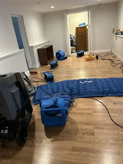 Air movers and a drying mat set on a wet hardwood floor