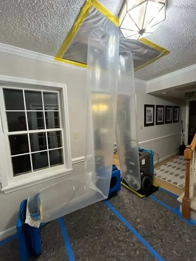 Plastic containment and an air scrubber set under a ceiling damaged by a roof leak