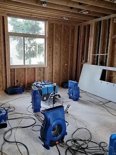 Air movers spread across a gutted room during structural drying