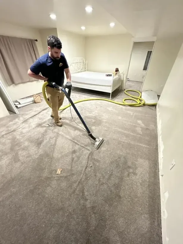 A technician pulling standing water off a floor with an extraction wand